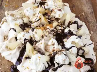 Торт безе з грушами, вершками, лісовими горіхами та шоколадним соусом.
