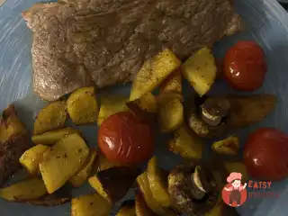 Стейки із запеченими картопляними часточками, коктейльними томатами та печерицями