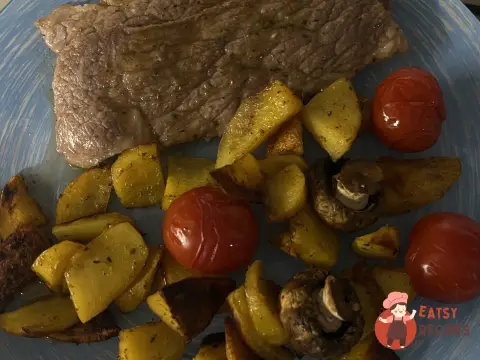 Стейки із запеченими картопляними часточками, коктейльними томатами та печерицями