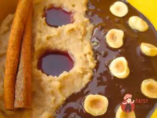 Манна каша з фундуком, темним шоколадом та журавлинно-гранатовим соусом.