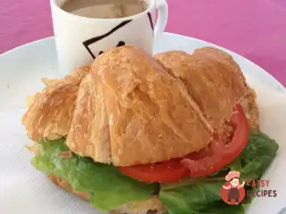 Круасан з тунцем, листям салату та помідором