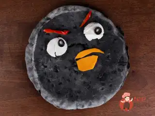 Чорна піца з фаршированими помідорами, руколою та соусом з тунця.